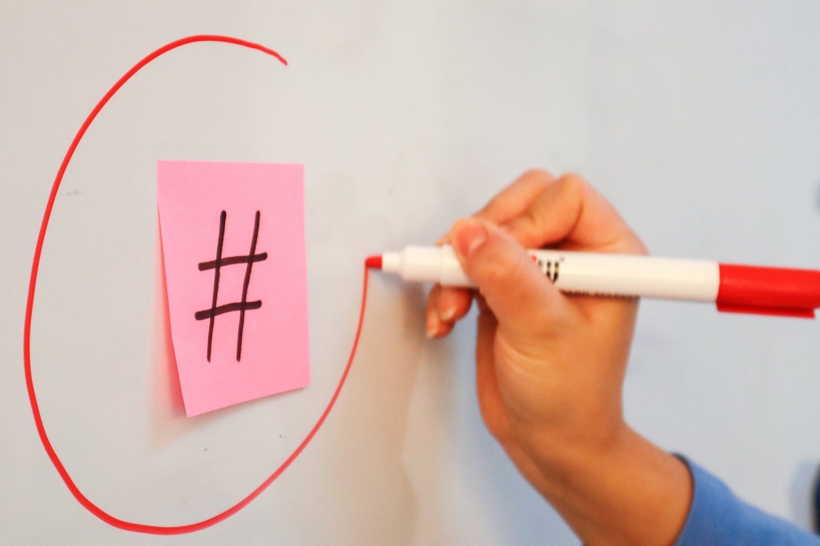a hand highlighting a hashtag on a white board with a red marker